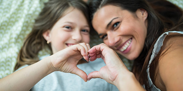 Mother and daughter putting hands together to form a heart shape