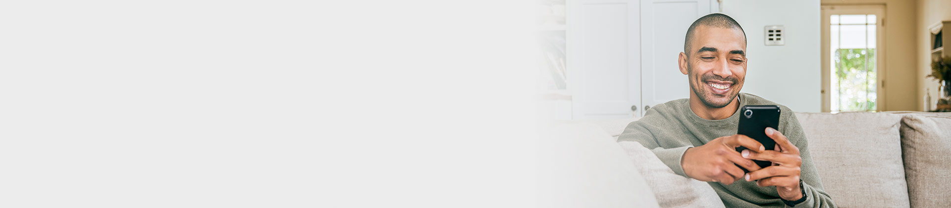 man smiling while looking at his phone