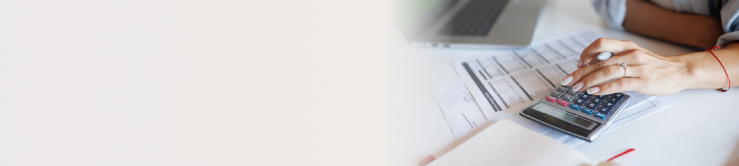 Woman's hand using a calculator that is sitting on top of paper bill