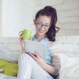 woman holding coffee cup and looking at tablet