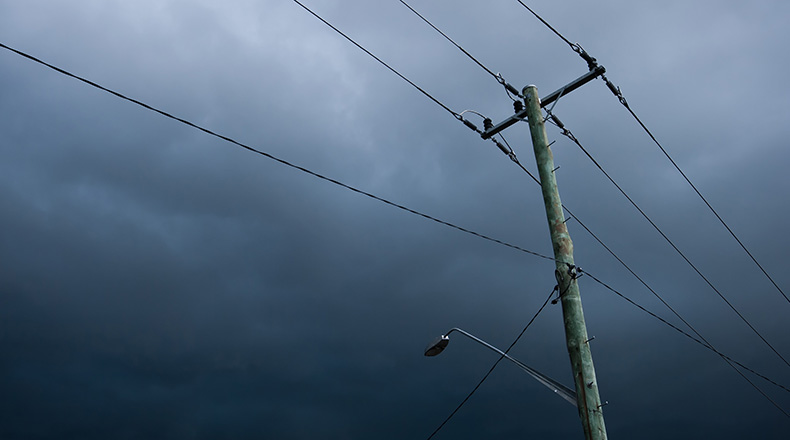 looking up at a utility pole with a dark storm sky in the background