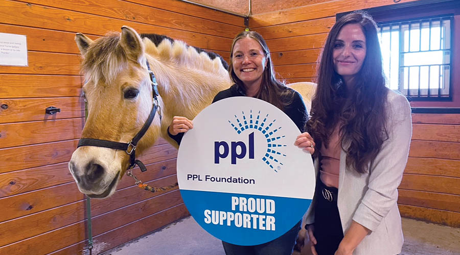 Two woman and a horse holding a sign that says PPL Foundation Supporter