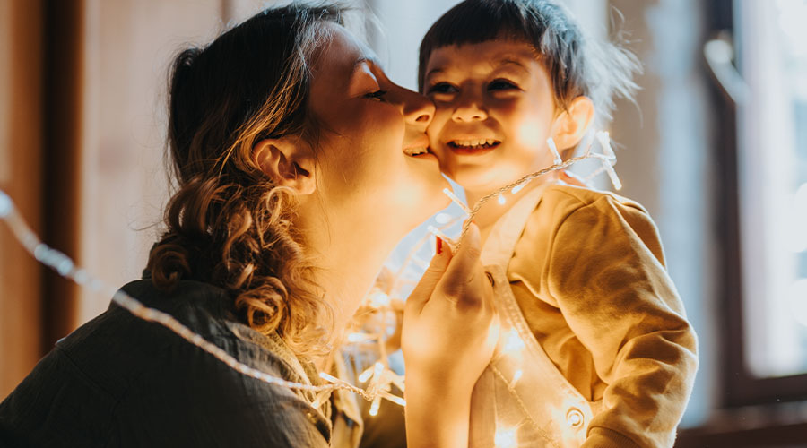 mother and young child playing with holiday lights
